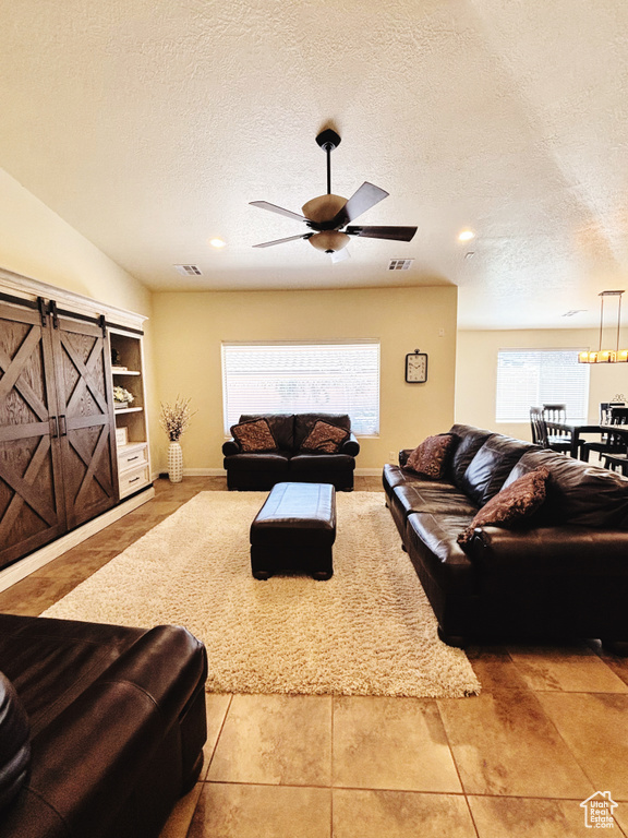 Tiled living area with a textured ceiling, ceiling fan, and recessed lighting
