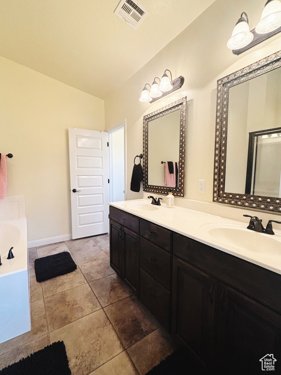 Bathroom with double vanity, a tub, and lofted ceiling
