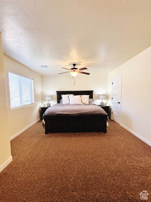 Carpeted bedroom with a textured ceiling and a ceiling fan