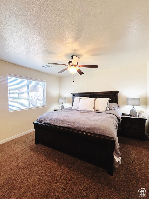 Bedroom with carpet, a textured ceiling, and a ceiling fan