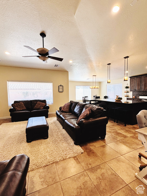 Living room with plenty of natural light, a textured ceiling, a ceiling fan, light tile patterned floors, and recessed lighting