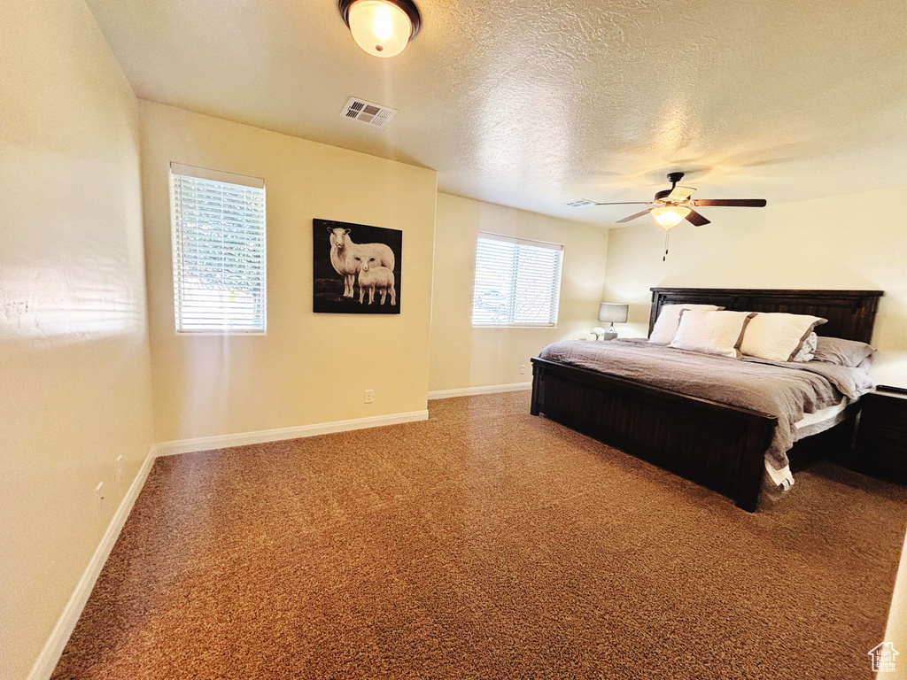 Carpeted bedroom with a ceiling fan and a textured ceiling