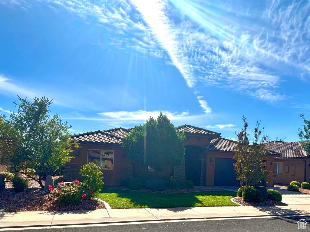 Mediterranean / spanish-style house featuring a tiled roof, concrete driveway, a garage, stucco siding, and a front lawn