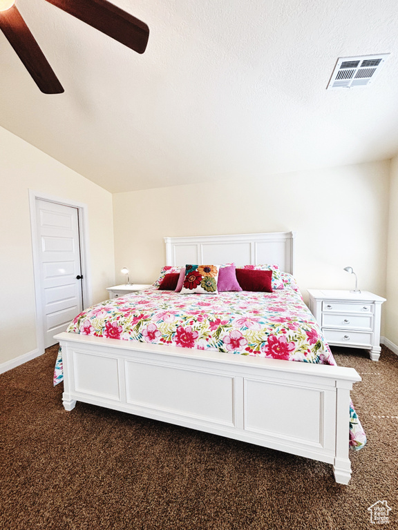 Bedroom featuring dark colored carpet, vaulted ceiling, and a ceiling fan