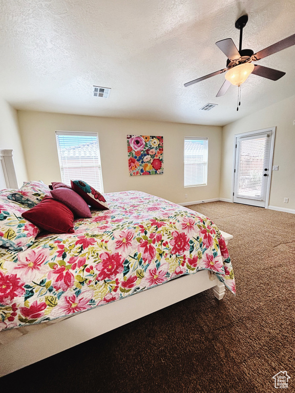 Carpeted bedroom featuring a textured ceiling and a ceiling fan