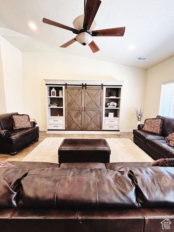 Living area featuring lofted ceiling, a textured ceiling, and a ceiling fan