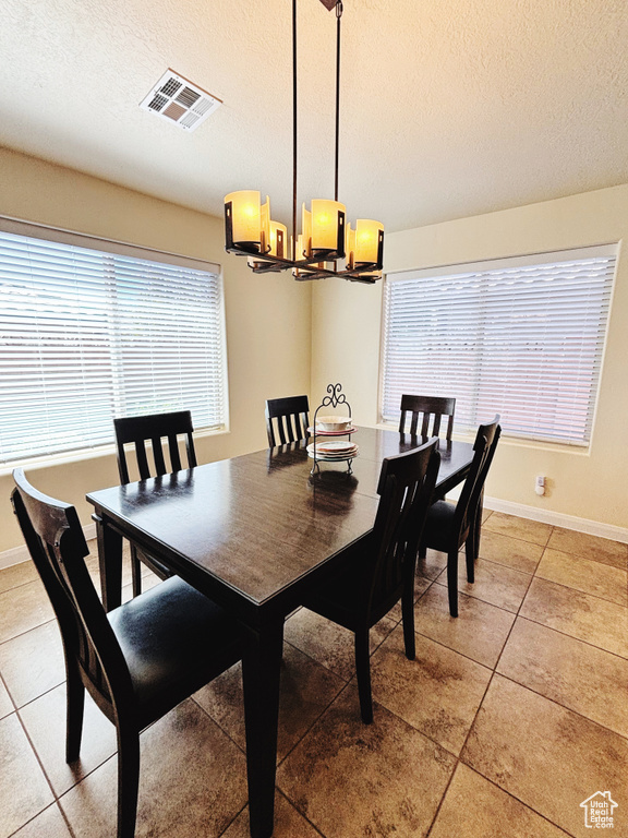 Dining area with a chandelier, a textured ceiling, and light tile patterned floors