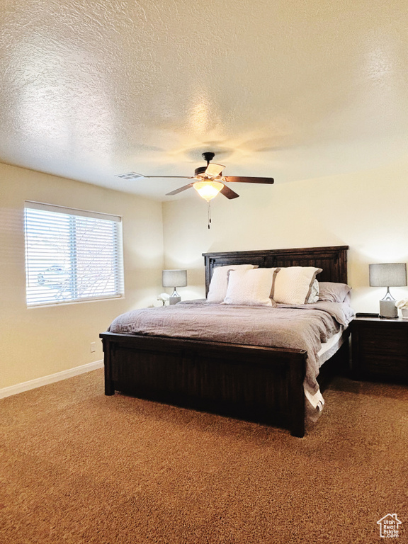 Carpeted bedroom with a textured ceiling and ceiling fan