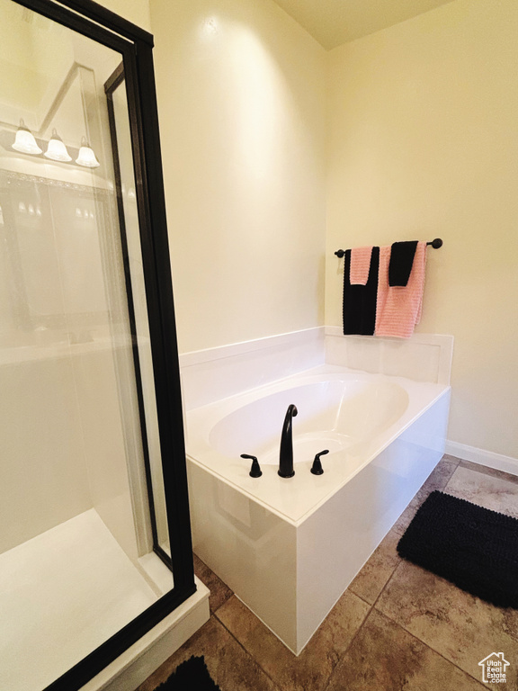 Full bathroom with a bath, a shower stall, and stone tile floors