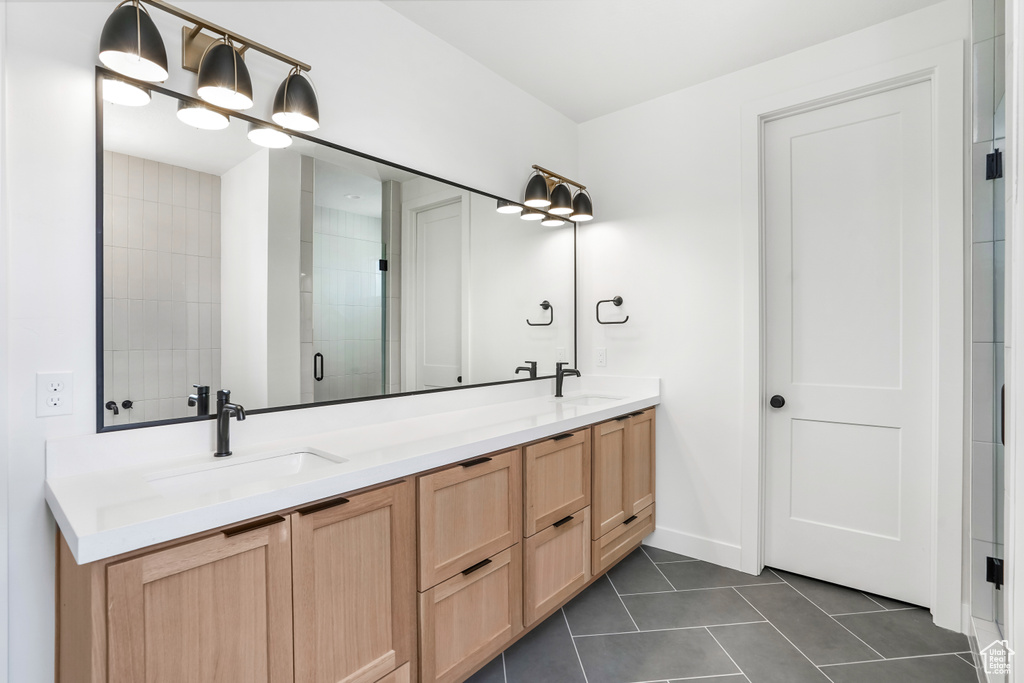 Bathroom featuring double vanity, tile patterned flooring, and a tile shower
