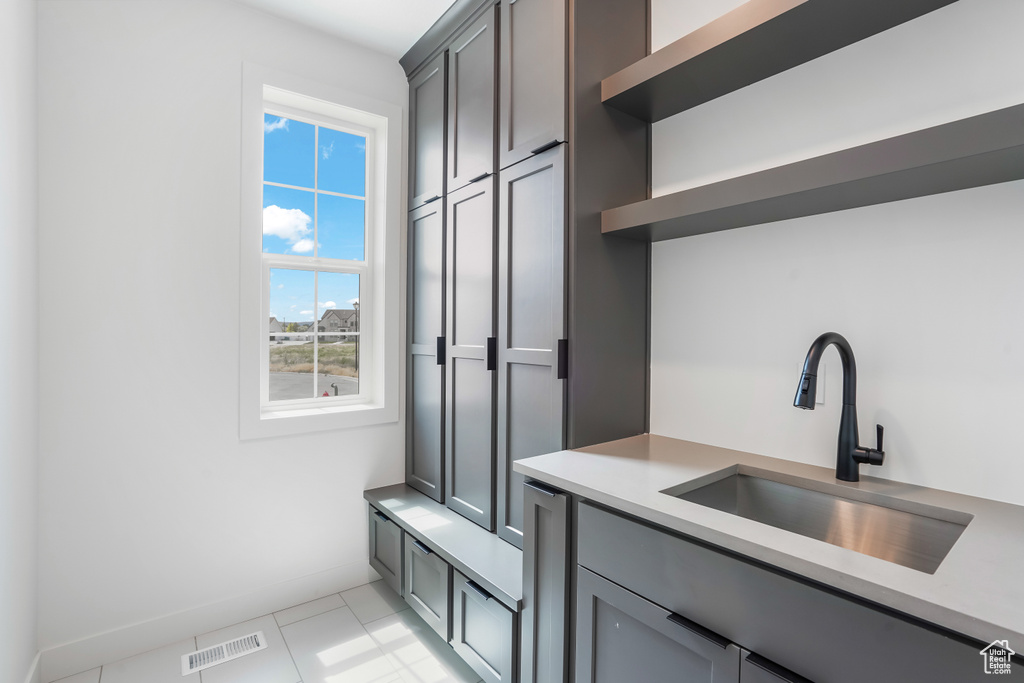 Kitchen featuring open shelves, light countertops, light tile patterned flooring, and gray cabinets