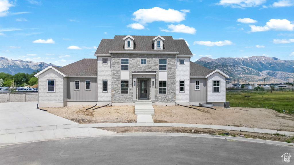 View of front of home with a mountain view, stone siding, and a shingled roof