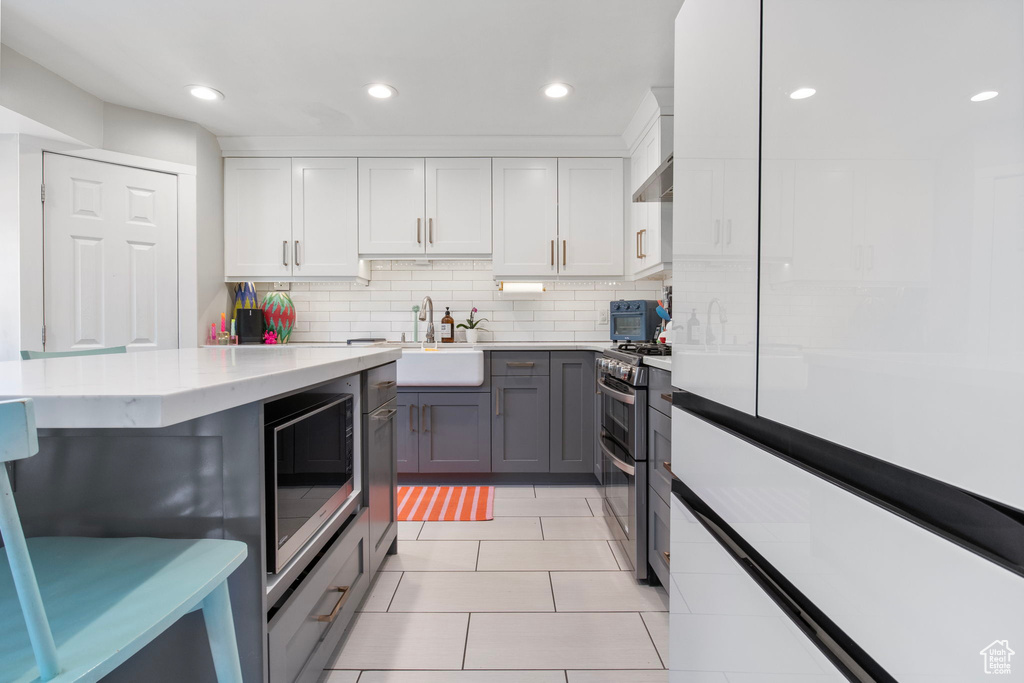 Kitchen featuring stainless steel appliances, gray cabinetry, recessed lighting, backsplash, and light tile patterned floors