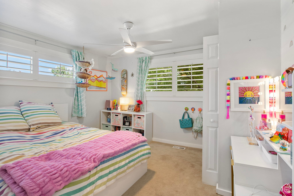 Bedroom with multiple windows, light carpet, and ceiling fan