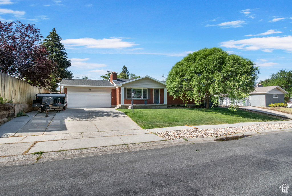 Single story home featuring an attached garage, concrete driveway, and a chimney