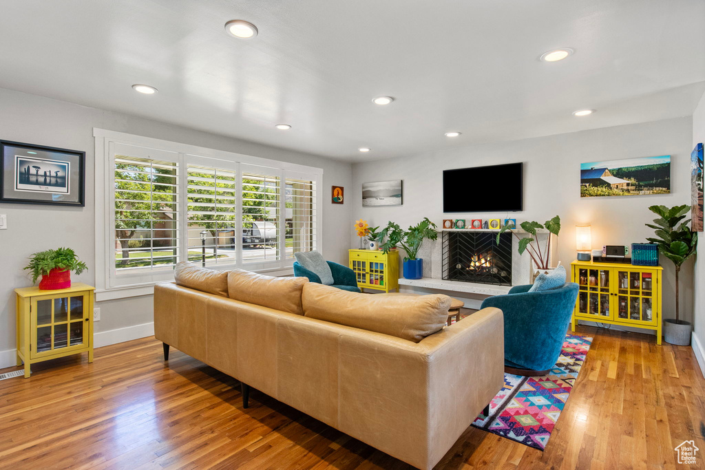 Living area with a lit fireplace, wood finished floors, and recessed lighting