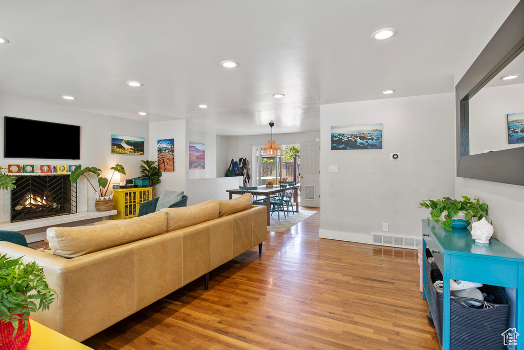 Living area featuring light wood-style flooring, recessed lighting, and a lit fireplace