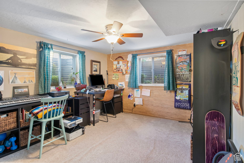 Carpeted office featuring a ceiling fan