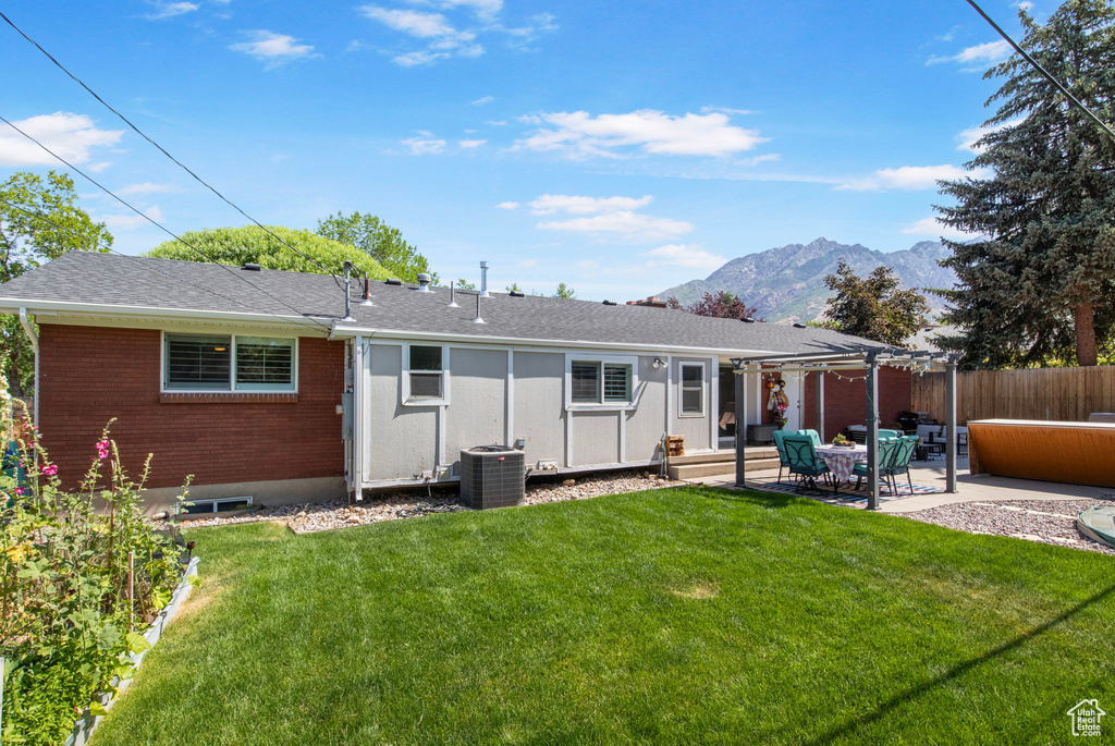 Back of house with a pergola, a mountain view, a patio, brick siding, and a shingled roof