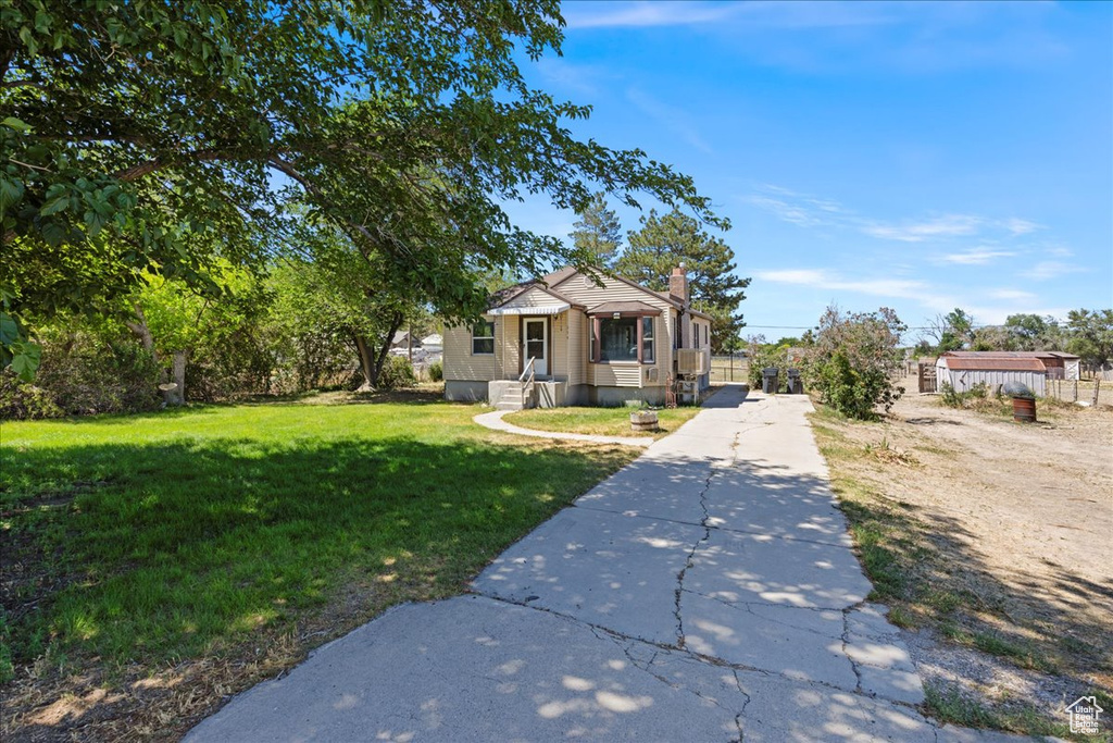 View of front of home with a front lawn, a chimney, and driveway