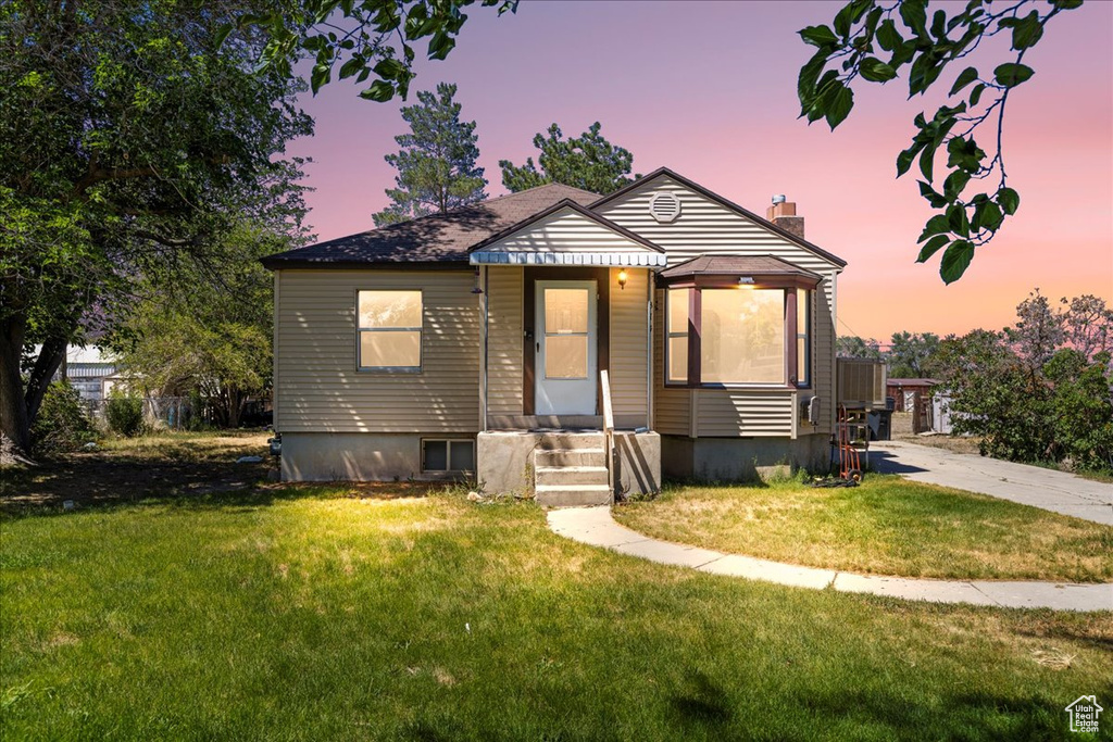 Bungalow-style home featuring a chimney and a front lawn