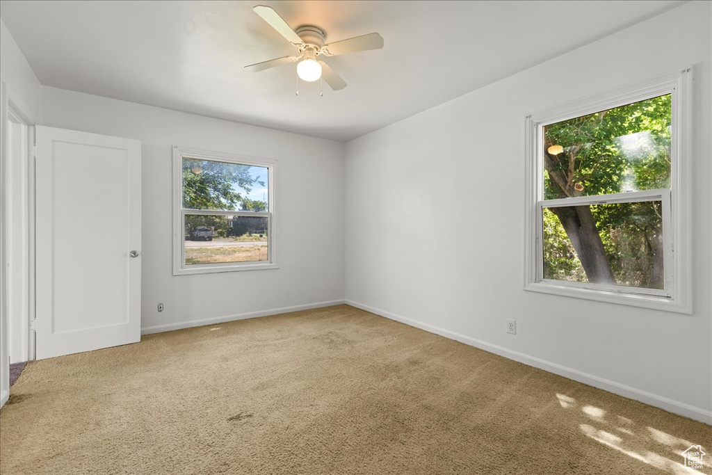 Carpeted spare room featuring baseboards and ceiling fan