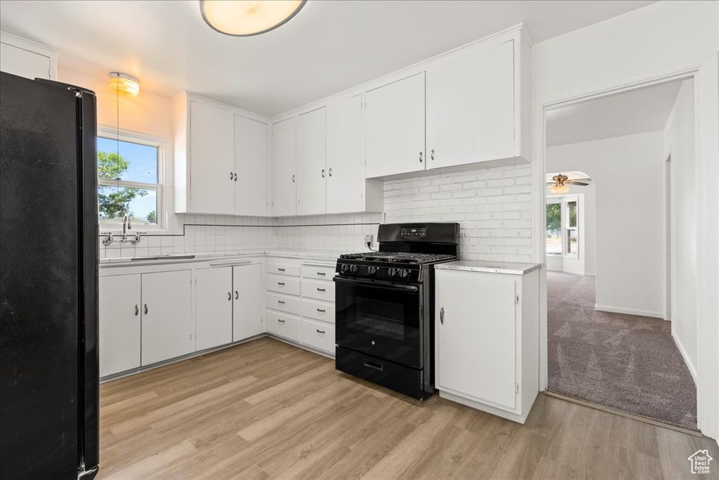 Kitchen with black appliances, light countertops, tasteful backsplash, and white cabinetry