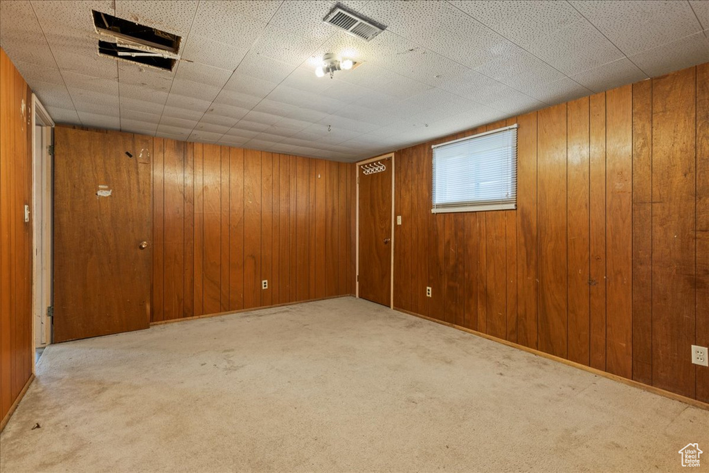 Carpeted empty room featuring wooden walls