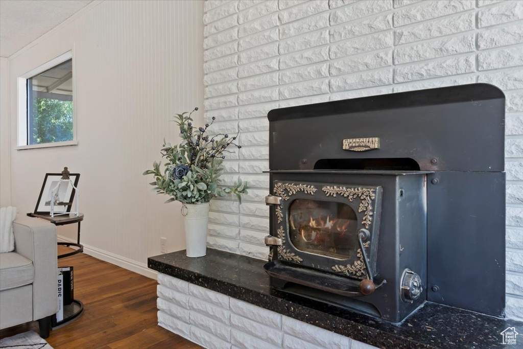 Detailed view of wood finished floors, a wood stove, and crown molding