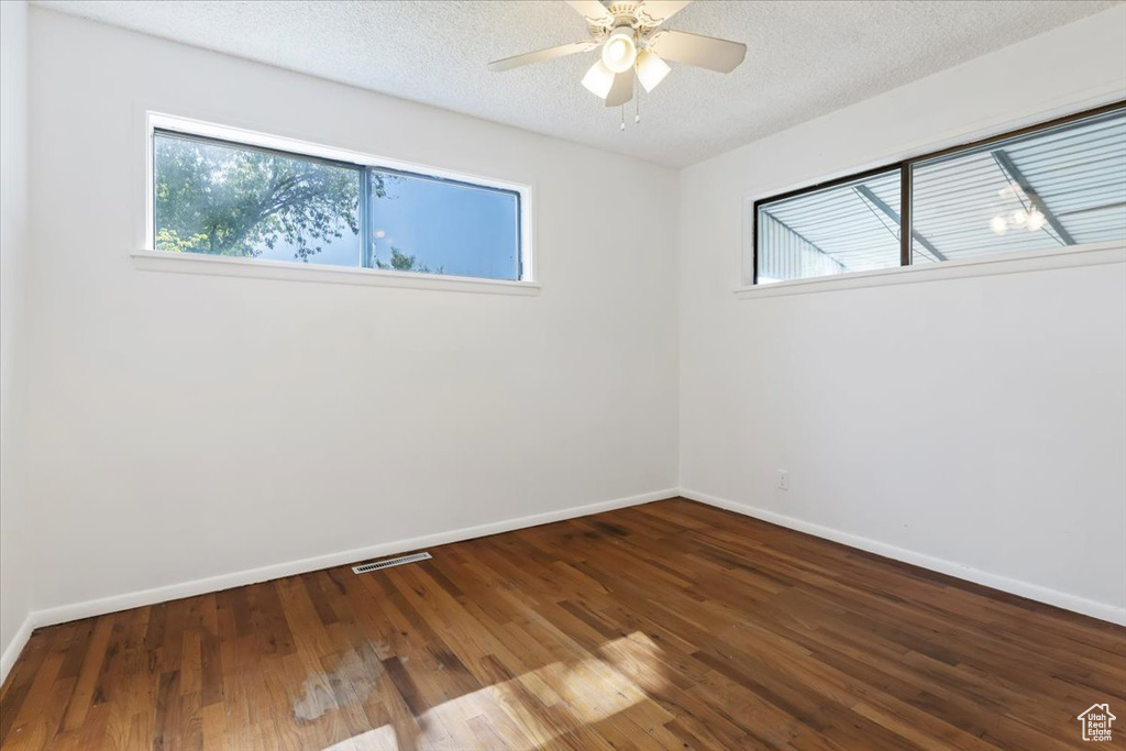 Unfurnished room featuring plenty of natural light, wood finished floors, a ceiling fan, and a textured ceiling
