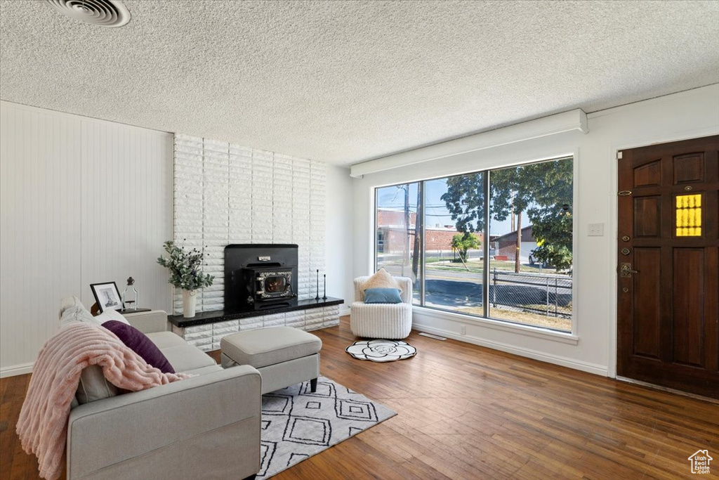 Living area featuring a wood stove, a textured ceiling, and wood finished floors