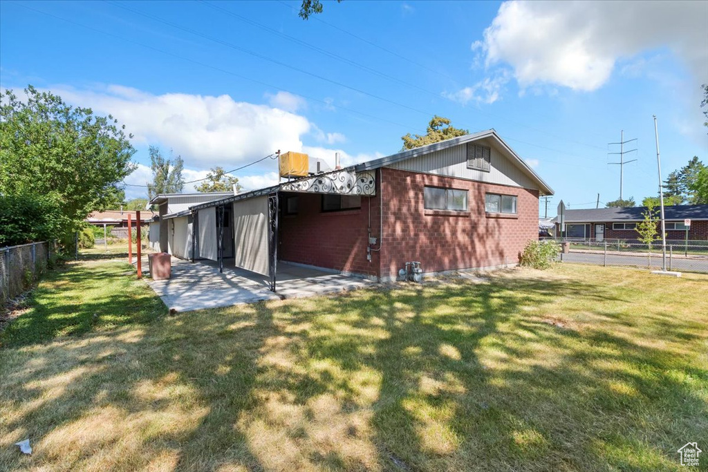 Rear view of property featuring brick siding, a fenced backyard, and a patio area