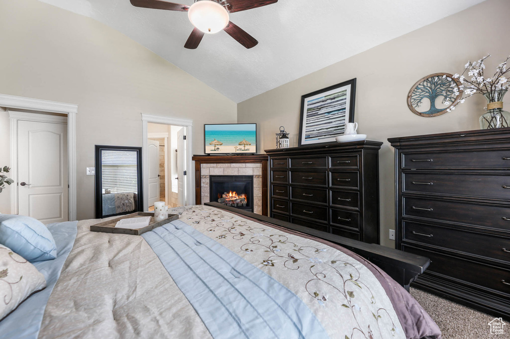 Carpeted bedroom featuring a fireplace, ceiling fan, and high vaulted ceiling