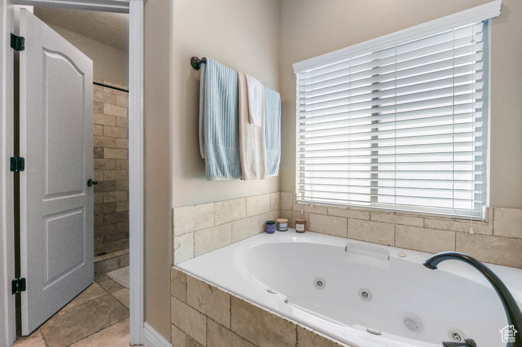 Bathroom with a tub with jets and tile patterned floors