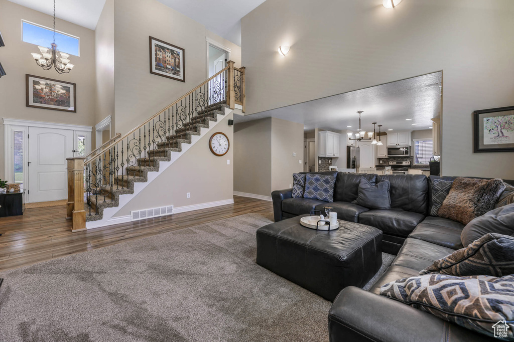Living room featuring a chandelier, a high ceiling, stairway, and wood finished floors