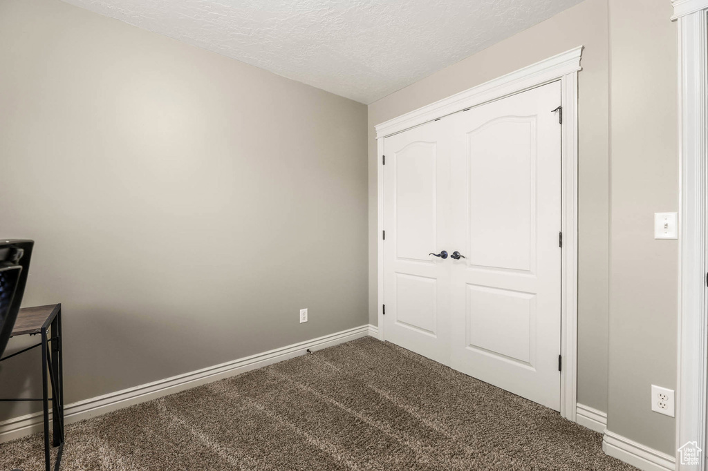 Unfurnished bedroom with carpet flooring, a textured ceiling, and a closet