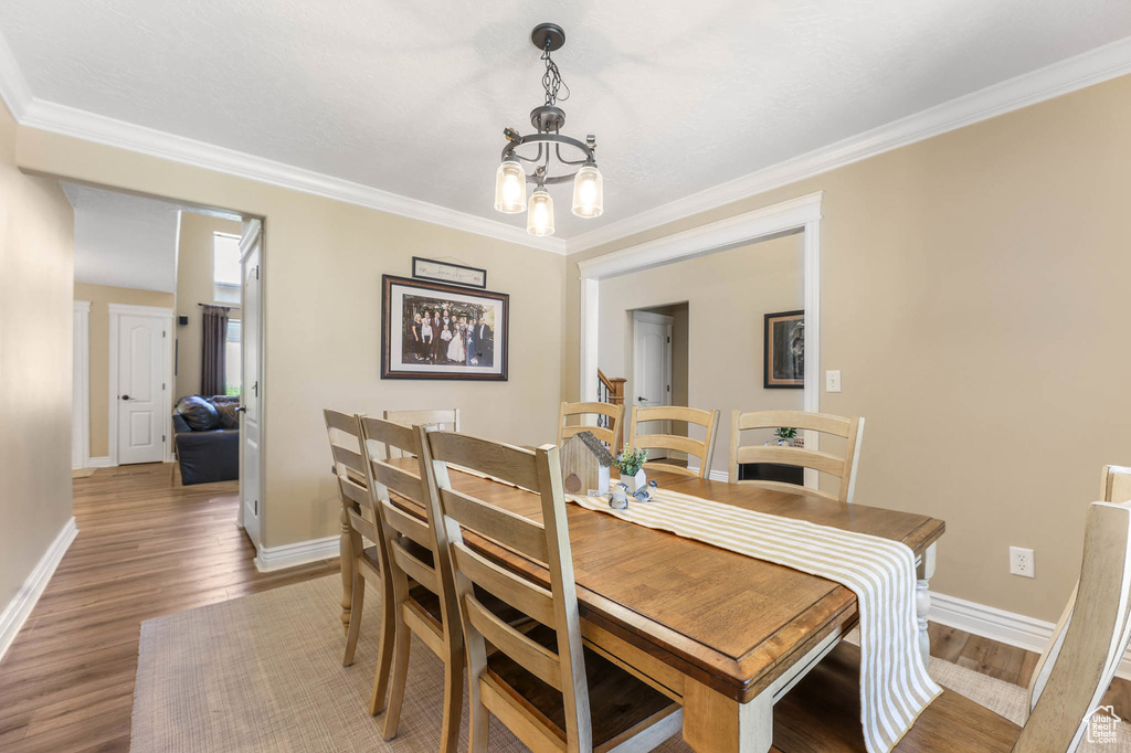 Dining area featuring wood finished floors, a chandelier, and crown molding