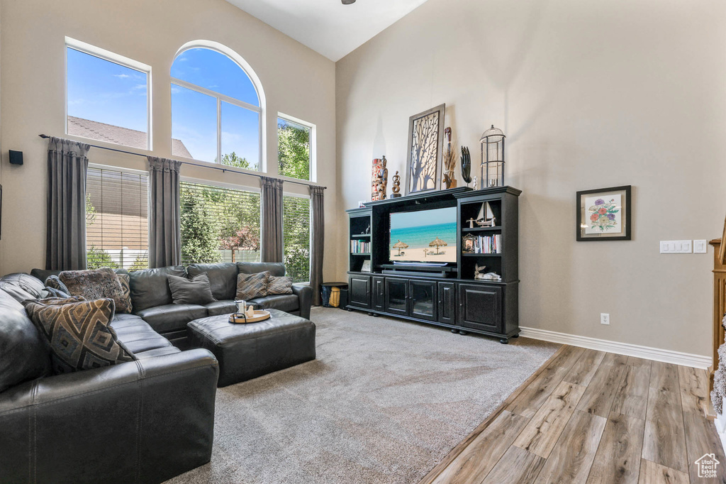 Living room with a high ceiling, light wood-style flooring, and healthy amount of natural light
