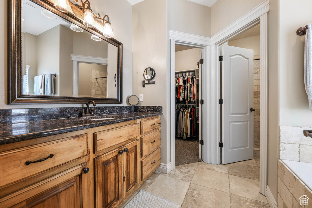Full bath featuring vanity, a spacious closet, and a tub