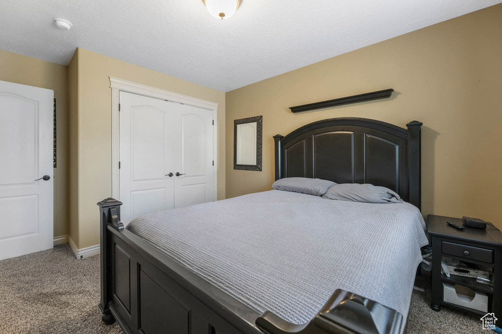 Bedroom with light colored carpet and a closet