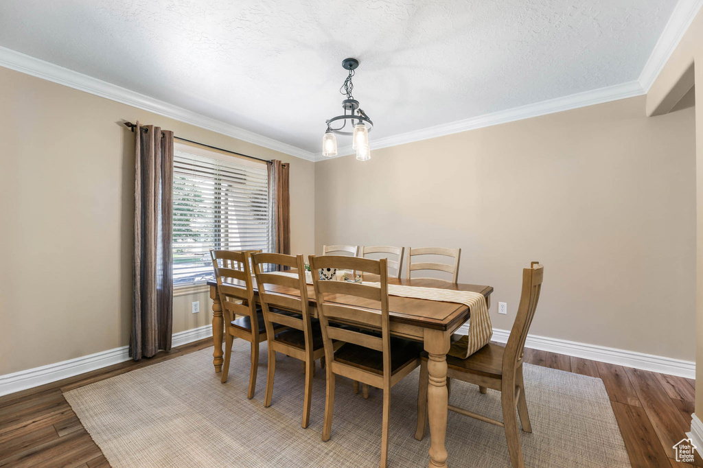 Dining room with ornamental molding, wood finished floors, and a chandelier