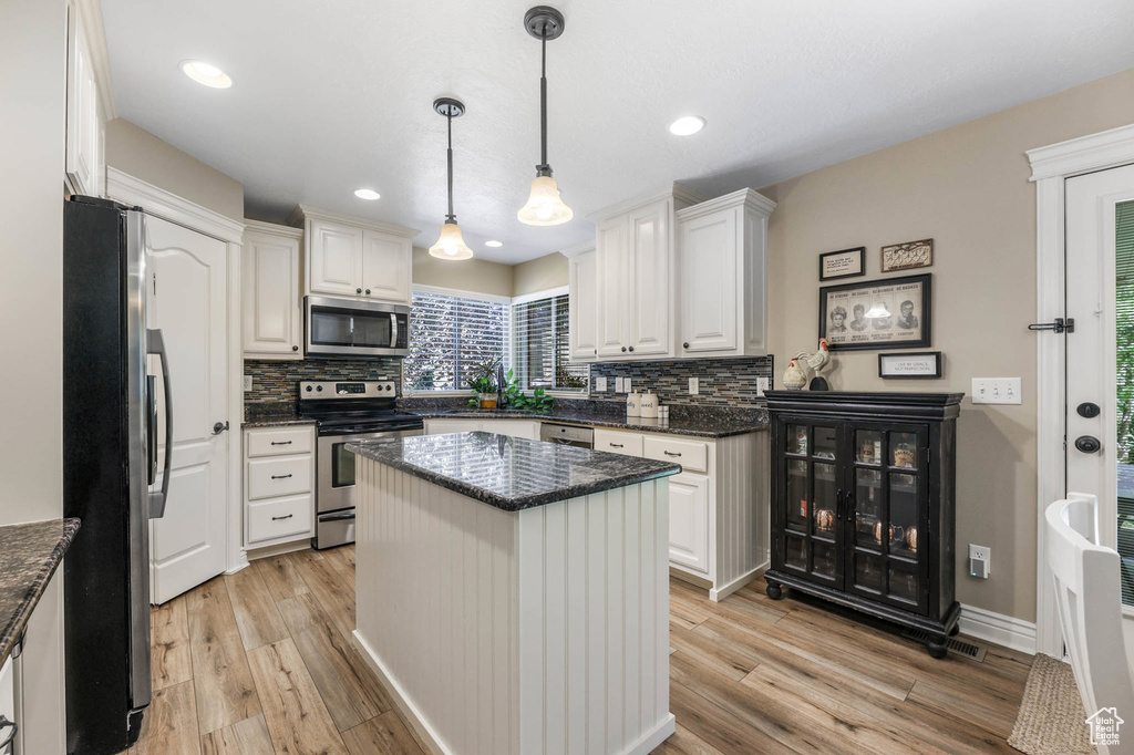 Kitchen featuring appliances with stainless steel finishes, backsplash, light wood-type flooring, white cabinetry, and recessed lighting