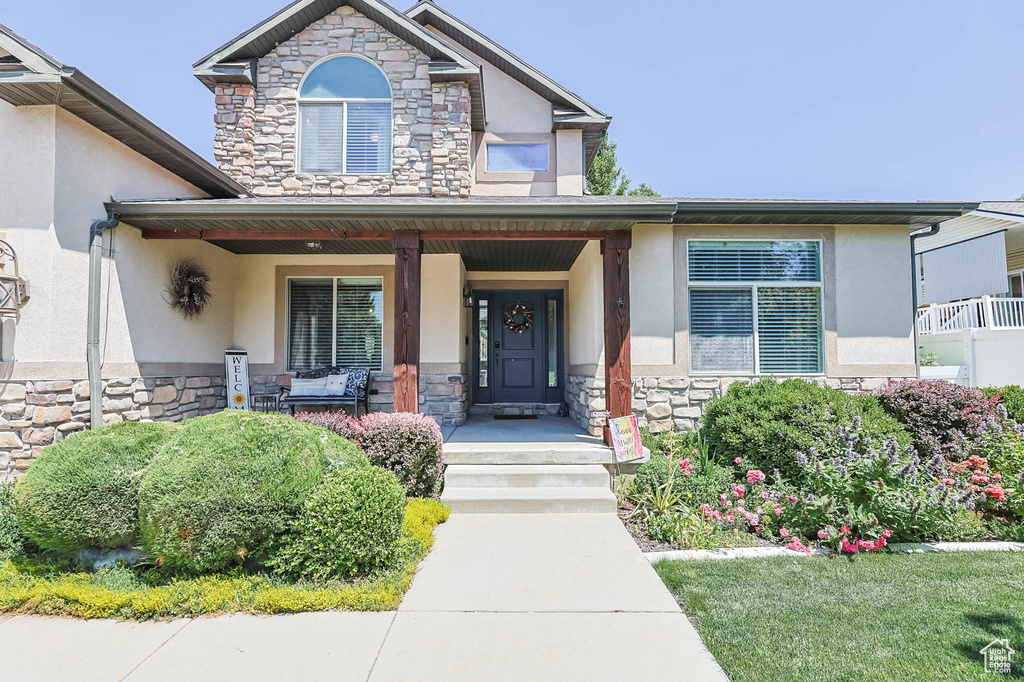View of front facade with stone siding, stucco siding, and covered porch