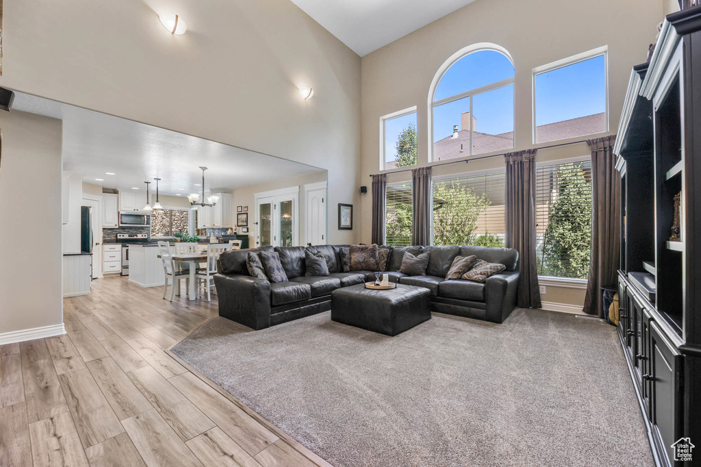 Living area featuring a chandelier, a towering ceiling, and light wood-style floors