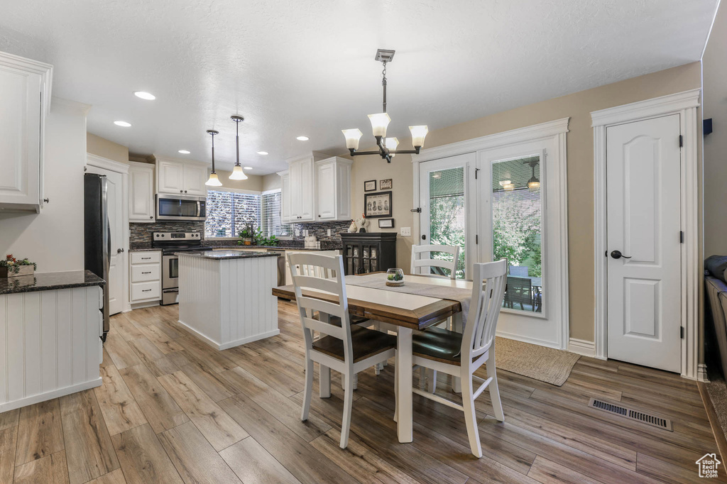 Dining space with light wood finished floors, a chandelier, and recessed lighting