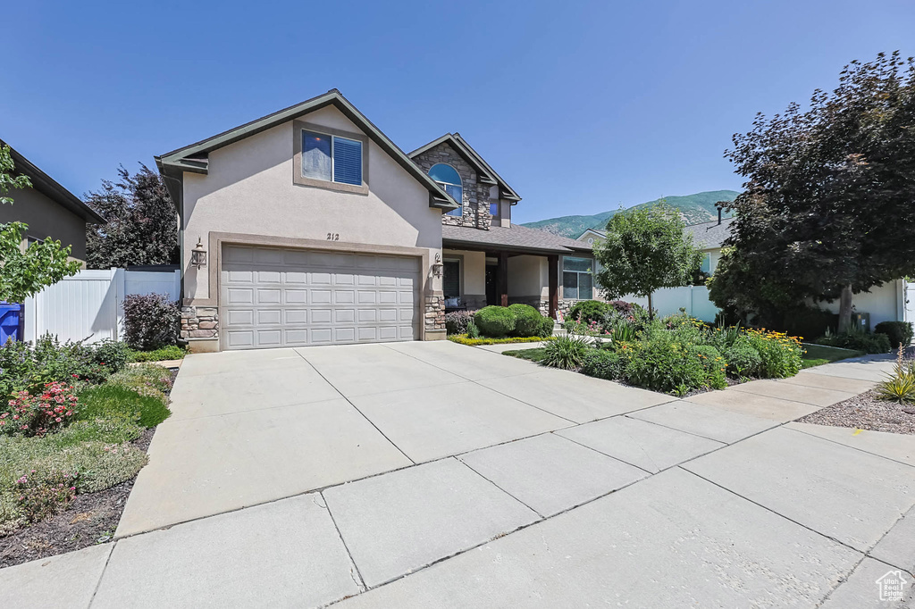 View of front of property featuring stucco siding, stone siding, a garage, driveway, and a mountain view
