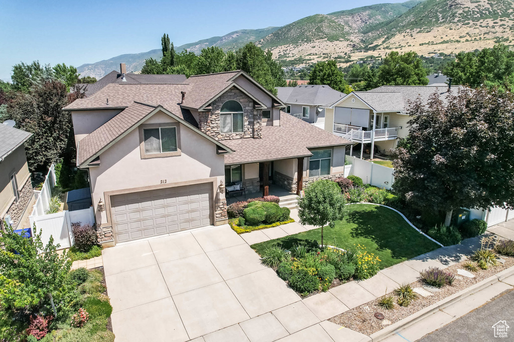 View of front of home featuring stone siding, stucco siding, a shingled roof, and concrete driveway