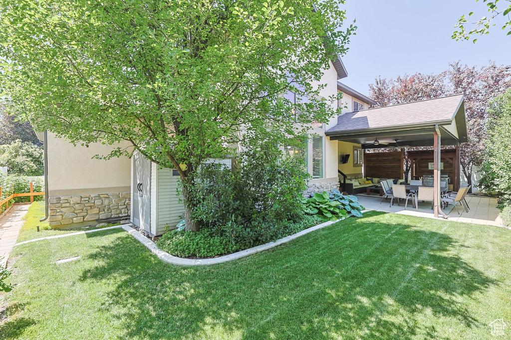 View of yard featuring an outdoor living space, ceiling fan, and a patio