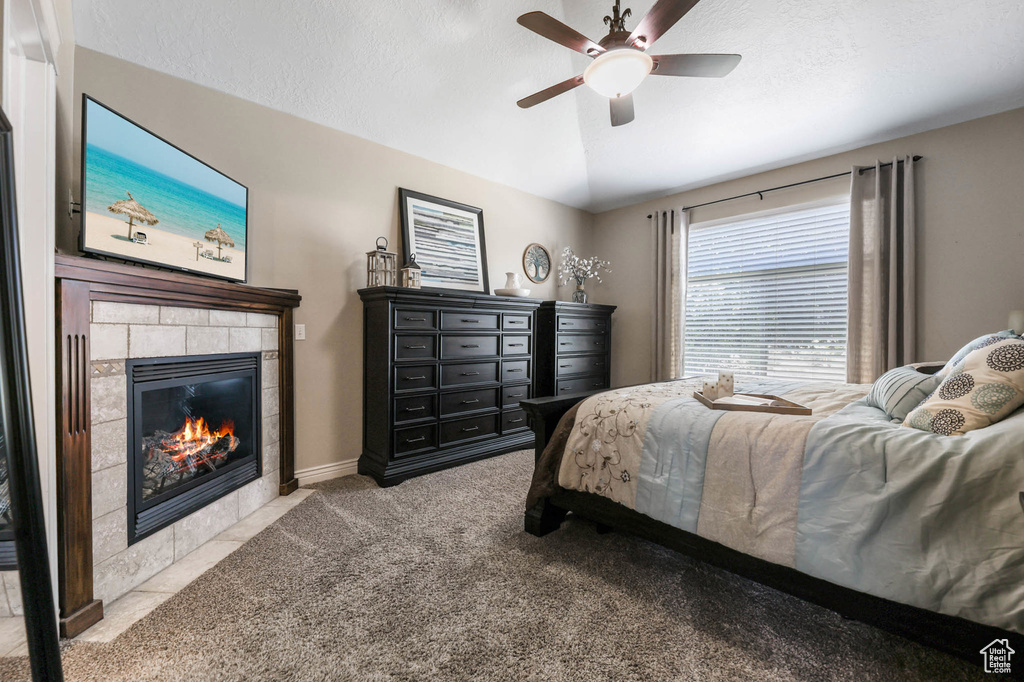 Carpeted bedroom with a fireplace, lofted ceiling, and a ceiling fan