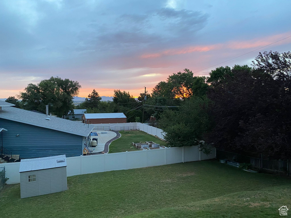 Yard at dusk with a fenced backyard and a storage shed
